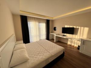 a bedroom with a white bed and a television at Dada Otel in Ezine