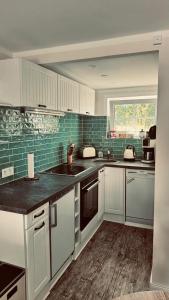 a kitchen with white cabinets and green tile at Joachims Ruhe in Joachimsthal +12 photos