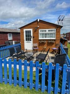 a blue fence in front of a wooden house at Sheppey Village Roxy in Leysdown-on-Sea