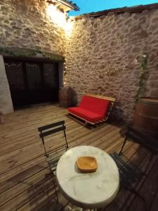 a wooden deck with a table and a red chair at La Pépite du Sauternais in Preignac