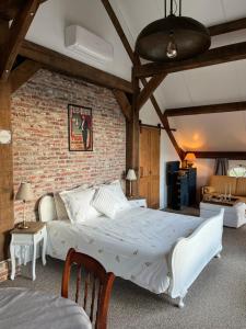 a bedroom with a white bed and a brick wall at B&B De Cootjes in Ossendrecht