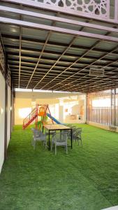 a room with a table and chairs and a playground at استراحة الوداد in Qurayyah
