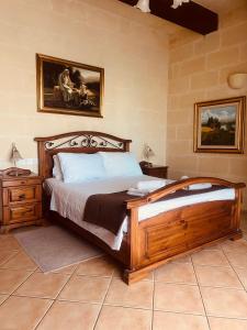 a bedroom with a wooden bed and a painting on the wall at Narcisa Farmhouse B&B in Nadur +78 photos