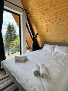 a bedroom with a bed with towels on it at A-frame Noa Cabin in Teşila