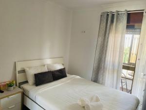 a bedroom with a white bed with a window at London Guest House in Caneças
