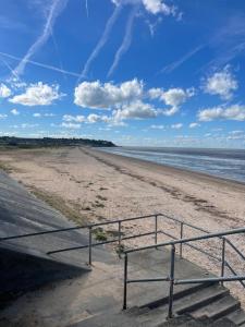 a sandy beach with a metal railing next to the ocean at Sheppey Village Ollie in Leysdown-on-Sea