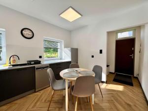 a kitchen with a table and chairs and a clock at Apartament Pod Wiatrakiem in Bęsia