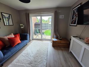 a living room with a blue couch and a sliding glass door at Olive & Ember - 1 Bed with private garden in Hythe