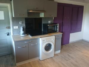 a kitchen with a washing machine and a microwave at Gite Atchoum in Hostun