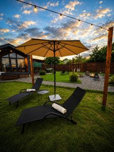 a patio with two chairs and an umbrella at ForRest будинок з басейном та чаном in Moshchun