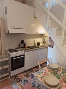 a kitchen with white cabinets and a sink and a stove at The Lake Chime in Colonno