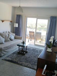 a living room with a couch and a table and a balcony at Two BR Sea View with Balcony and Pool Paphos in Khlorakas +30 photos