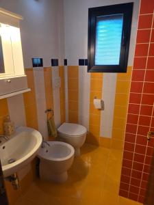 a bathroom with a toilet and a sink and a window at Lemon House in Avola