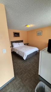 a hotel room with a bed with white sheets at Blue Mountain Motel in Okanogan