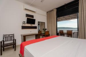 a bedroom with a bed and a desk and a window at Sahana beach in Galle