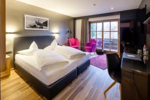 a bedroom with a bed and a desk and chairs at Boutique Hotel Gams in Oberstdorf