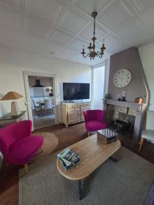a living room with purple chairs and a table at havre de paix in Saint-Junien