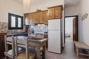 a kitchen with a table and a white refrigerator at Philoxenia Apartments in Karpathos
