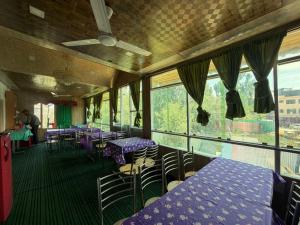 a restaurant with purple tables and chairs and windows at Hotel New Heaven Canal in Srinagar