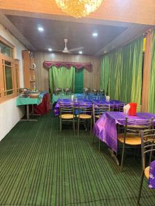 a restaurant with purple tables and chairs and green curtains at Hotel New Heaven Canal in Srinagar