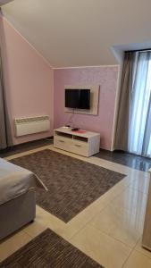 a bedroom with a tv on a pink wall at SOBE Svilajnac in Svilajnac