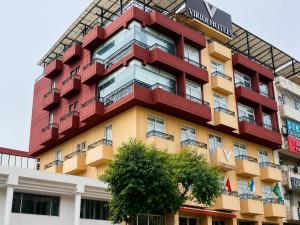a red and yellow building with a tree in front of it at Viridi Hotels Islamabad in Islamabad
