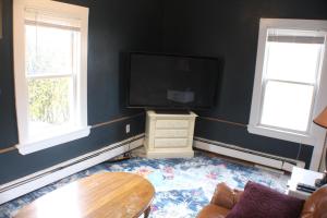 a living room with a flat screen tv and two windows at Pet friendly cottage near Boston in Canton