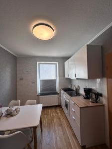a kitchen with white cabinets and a table with chairs at Ferienwohnung Waldblick in Harrislee