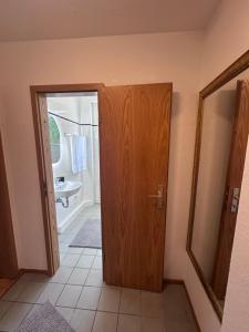 a bathroom with a wooden door and a sink at Ferienwohnung Waldblick in Harrislee