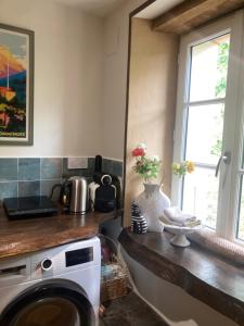 a kitchen with a washing machine and a window at Appartement à colombages indépendant avec piscine partagée avec le proprietaire in Ponsan-Soubiran