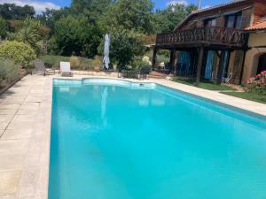 a swimming pool with blue water in front of a house at Appartement à colombages indépendant avec piscine partagée avec le proprietaire in Ponsan-Soubiran