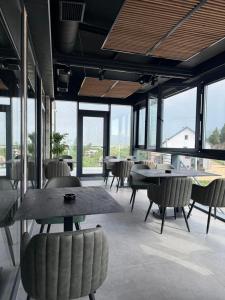 a dining room with tables and chairs and windows at Motel Gradina in Bosansko Grahovo