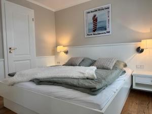 a white bed with blankets and pillows on it at Haus Magnus SeaSide in Sylt +34 photos