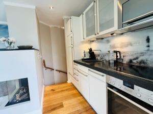 a kitchen with white cabinets and a black counter top at Haus Magnus SeaSide in Sylt
