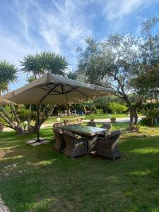 a table and chairs under an umbrella in the grass at Un Passo Dal Mare in Lido di Fermo