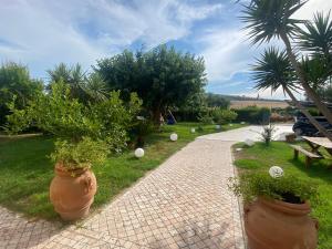 a brick walkway with large pots of plants in a park at Un Passo Dal Mare in Lido di Fermo