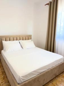 a bed with white sheets and pillows in a room at Villa DEA in Velipojë
