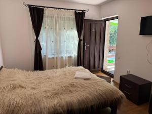 a bedroom with a large furry bed with a window at Casa Mario in Dragoslavele