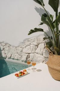 a plate of fruit and two glasses of wine on a table at Anome Experience Hotel in Ornos