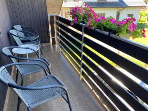 a balcony with chairs and flowers on a fence at Apartmán Hanka in Rožnov pod Radhoštěm