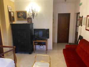a living room with a tv and a red couch at Vintage Apartment in Vila Nova de Milfontes