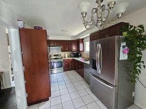 a kitchen with a stainless steel refrigerator and a chandelier at Cozy and comfortable home - Living room and Kitchen is shared in Pickering +5 photos