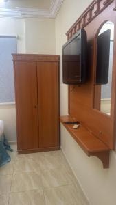 a room with a television and a cabinet with a mirror at فندق منازل الراشدين in Az Zahrāʼ