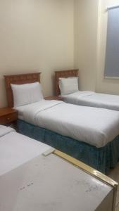 a room with two beds and a window at فندق منازل الراشدين in Az Zahrāʼ