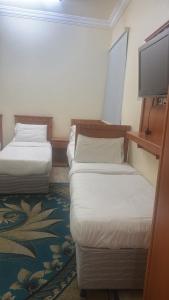 a hotel room with two beds and a flat screen tv at فندق منازل الراشدين in Az Zahrāʼ +4 photos