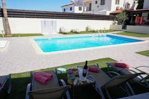 a pool with chairs and a table with a bottle of wine at Villa Paradise Complex - Pyla Larnaca in Pyla +19 photos