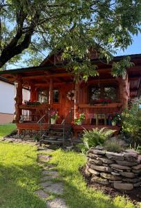 a log cabin with flowers in the front of it at Chalúpka u líšky Elišky in Ždiar