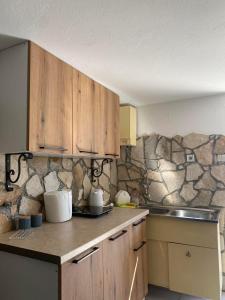 a kitchen with wooden cabinets and a stone wall at Villa Radis in Dobra Voda