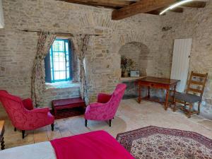 a bedroom with pink chairs and a table and a desk at Chambre entrée indépendante dans tour du 15ème siècle in Mauvières