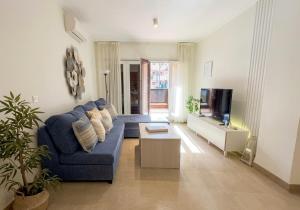 a living room with a blue couch and a tv at Musa apartamentos in El Ejido